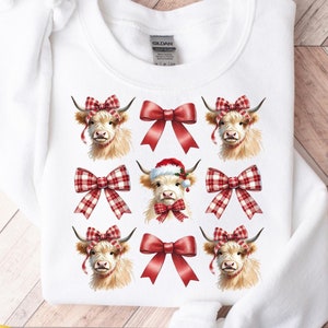 以下が含まれることがあります： 赤いリボンとサンタ帽をつけたハイランド牛の繰り返し模様が特徴の白いスウェットシャツ。牛は薄茶色の毛皮と濃い色の角をしています。スウェットシャツには「COMMERCIAL LICENSE INCLUDED! Hi-Res Optimized 300 DPI PNG」と書かれています。