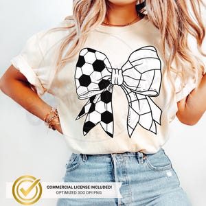May include: Black and white graphic of a football bow. The bow is made of two footballs, one on each side, with the laces of the footballs forming the bow. The bow is on a white t-shirt.