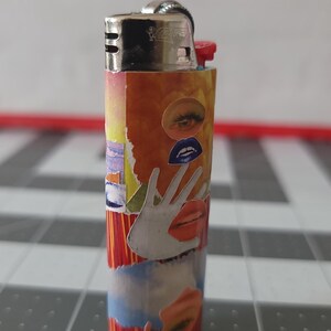 May include: A red, yellow, and blue lighter with a collage of images on the side. The images include a hand, an eye, and lips.