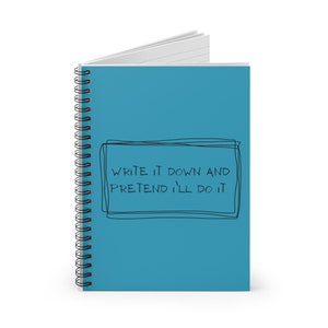 May include: A teal spiral-bound notebook. The cover has the text "WRITE IT DOWN AND PRETEND I'LL DO IT" in a black, handwritten font within a black outlined box. The notebook's pages are lined and the spiral binding is silver.