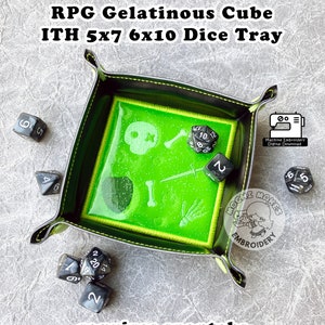 Könnte beinhalten: Ein schwarzes Würfeltablett mit einem grünen, glitzernden, gallertartigen Würfeldesign. Das Tablett hat ein Totenkopf- und Knochenkreuz, Knochen und ein Schwertdesign. Das Tablett ist mit "RPG Gelatinous Cube ITH 5x7 6x10 Dice Tray" und "requires snaptabs" beschriftet.