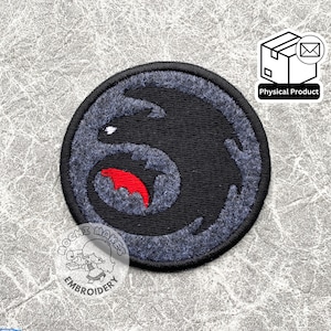 May include: Black and grey embroidered patch featuring a stylised dragon with red accents. The patch is circular and has a textured fabric.