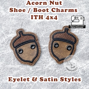 Puede incluir: Dos abalorios marrones de nuez de bellota para zapatos o botas, con costuras negras y ojales. Los abalorios miden 4x4 pulgadas y son diseños de bordado a máquina. El texto "Acorn Nut Shoe / Boot Charms ITH 4x4" y "Eyelet & Satin Styles" también está en la imagen.