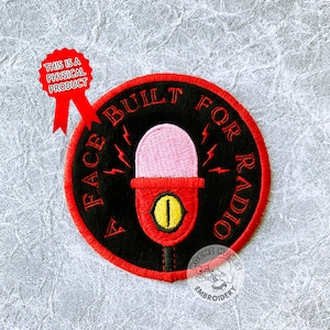 Op de afbeelding: Een geborduurde zwarte en rode patch met een microfoon en de tekst "A Face Built For Radio".