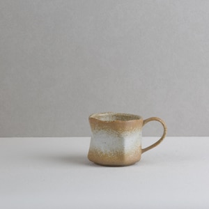 May include: A small, hand-thrown ceramic mug with an irregular, faceted shape. The exterior features a textured, earthy brown base glaze that transitions into a mottled white glaze around the center, finished with a single curved handle on the side.