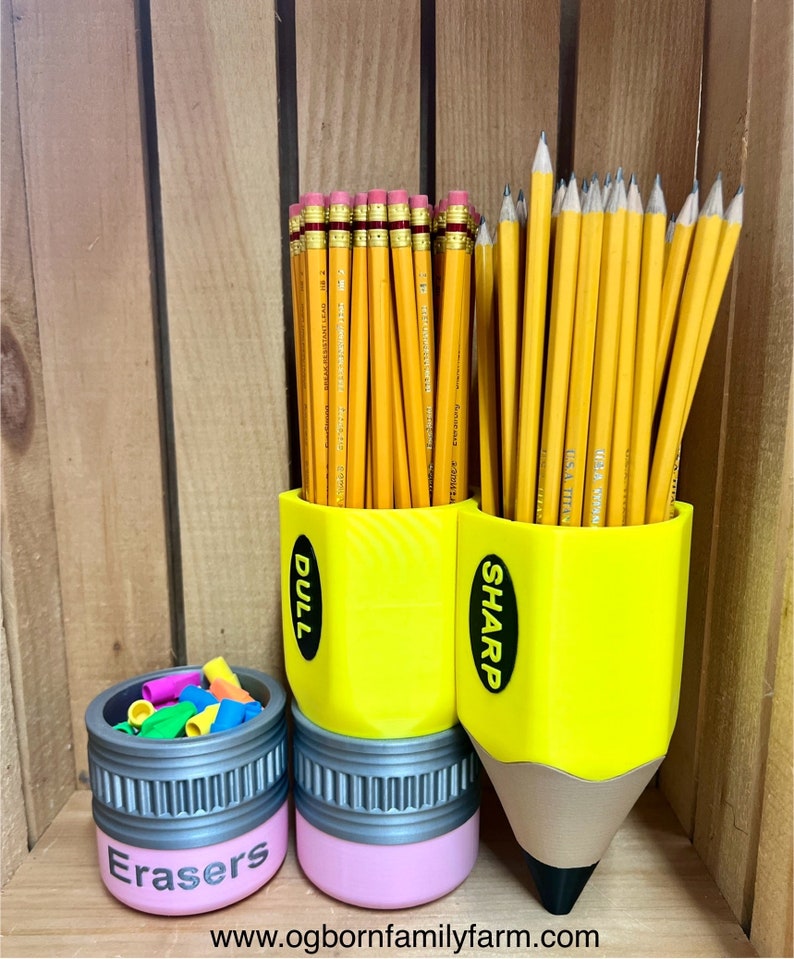 May include: A pencil-themed desk organizer set. Includes a small pink container labeled "Erasers" and two yellow pencil-shaped holders, one labeled "Dull" and the other "Sharp", filled with pencils. The pencil holders are 3D printed.
