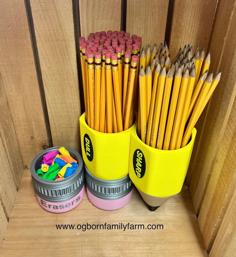 May include: A yellow pencil-shaped desk organizer with the word "DULL" and "SHARP" on the sides, filled with yellow pencils. A small container with the word "Erasers" on the side is filled with colorful erasers. The website address is at the bottom.