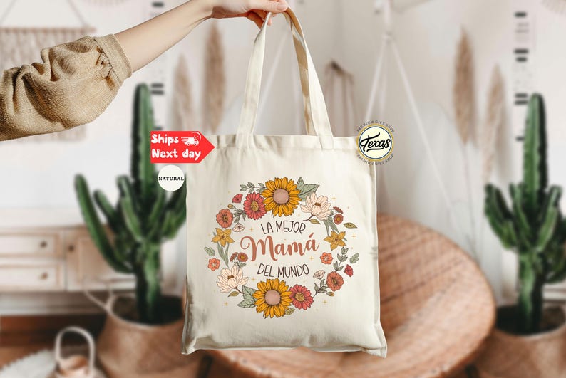 May include: A white canvas tote bag with a floral design and the text "La Mejor Mam&aacute; Del Mundo".