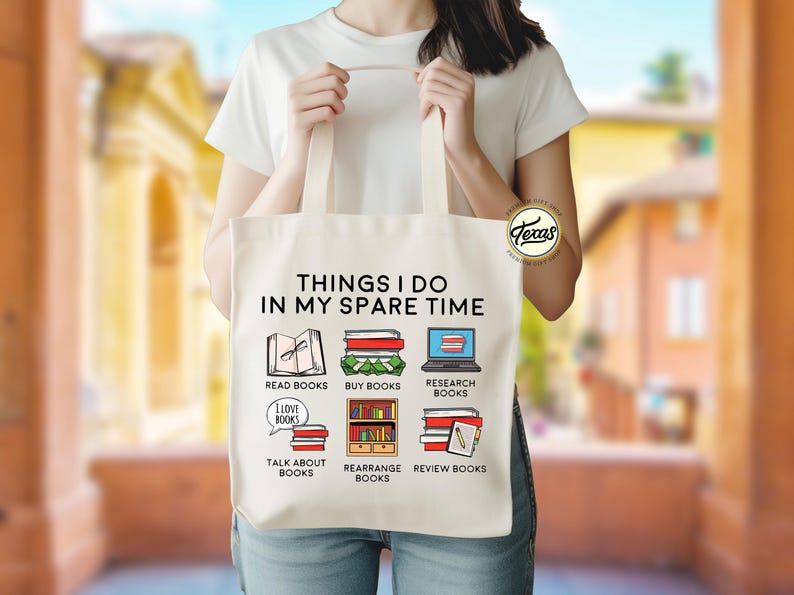 Pu&ograve; includere: Una borsa di tela bianca con il testo "Things I do in my spare time" e illustrazioni di libri. Le illustrazioni includono "Read Books", "Buy Books", "Research Books", "Talk About Books", "Rearrange Books" e "Review Books".