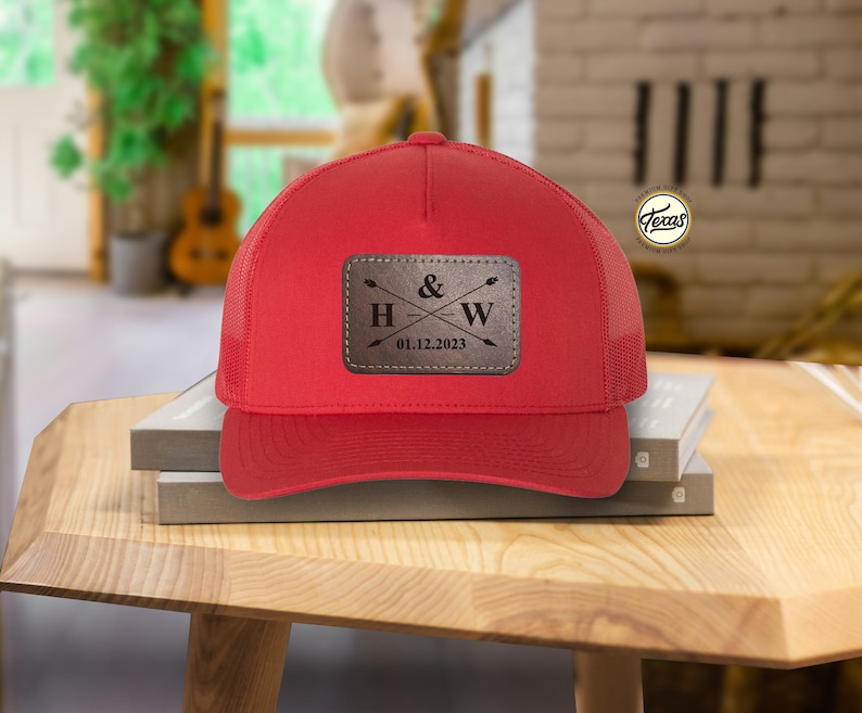May include: Red trucker hat with a brown leather patch that says "H & W" with crossed arrows and the date "01.12.2023".
