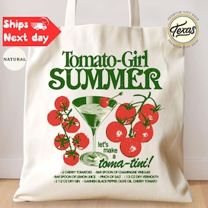 Peut inclure: Sac fourre-tout cr&egrave;me avec un graphisme vert et rouge. Le design pr&eacute;sente les mots "Tomato-Girl SUMMER" et un verre &agrave; cocktail avec des tomates. Le texte "let's make a toma-tini!" est &eacute;galement inclus.