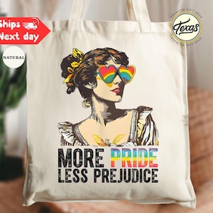 May include: A natural canvas tote bag featuring a vintage illustration of a woman wearing rainbow heart-shaped sunglasses. The text "MORE PRIDE LESS PREJUDICE" is printed below the illustration. The bag has a "Texas Premium Gift Shop" logo.