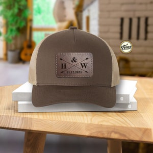 May include: Brown and tan trucker hat with a brown leather patch that says "H & W" with arrows and the date "01.12.2023".