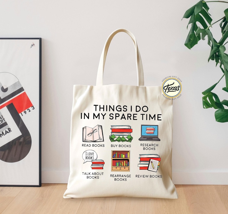 Pu&ograve; includere: Una borsa tote in tela bianca con il testo "Things I do in my spare time" stampato in nero. La borsa presenta illustrazioni di libri e il testo "Read books", "Buy books", "Research books", "Talk about books", "Rearrange books" e "Review books".