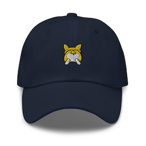 Puede incluir: Una gorra de béisbol azul marino con un perro de dibujos animados amarillo y blanco bordado en la parte delantera.