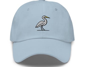 Pode incluir: Um boné de beisebol azul claro com uma garça branca bordada com um bico amarelo.
