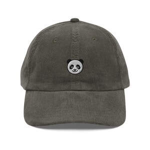 Può includere: Cappellino da baseball in velluto a coste verde oliva con un piccolo ricamo di un panda. Il panda ha dettagli in bianco e nero. Il cappellino ha una visiera curva e un cinturino regolabile. Un accessorio casual.