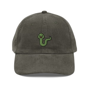 Può includere: Un cappello da baseball in velluto a coste verde scuro con un serpente verde ricamato con una lingua rossa.