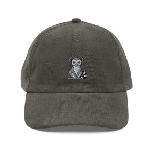 Könnte beinhalten: Eine grüne Cord-Baseballkappe mit einem gestickten Bild eines Lemurs, der auf seinen Hinterbeinen sitzt.