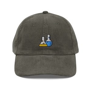 May include: A dark green corduroy baseball cap with an embroidered design of two beakers, one with blue liquid and the other with yellow liquid.