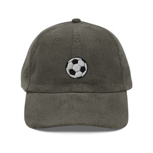 May include: A dark green corduroy baseball cap with a white and black embroidered football on the front.