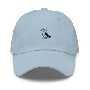 Op de afbeelding: Lichtblauwe baseballpet met een geborduurde blauwvoetgent. De pet heeft een gebogen klep en een verstelbare band. De vogel is afgebeeld in wit, zwart en blauw, voor een casual uitstraling.