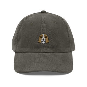 Puede incluir: Gorra de béisbol de pana verde oliva con una imagen bordada de la cara de un beagle en marrón, blanco y beige. La gorra tiene una visera curva y un cierre de correa de tela.
