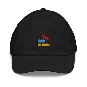 May include: Black baseball cap with a curved brim. The cap features an embroidered design of three colorful toy building blocks: red, blue, and yellow. The cap is made of a soft fabric and has an adjustable strap.