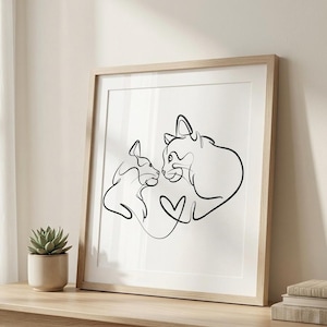 May include: A framed art print featuring a minimalist line drawing of two cats facing each other, with a heart shape formed by the lines. The artwork is in black on a white background, set in a light wood frame.