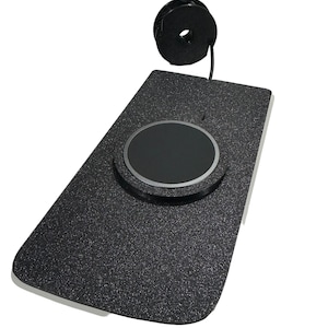 May include: A black wireless charging pad with a textured surface and a circular charging area. A black USB cable is attached and coiled. The pad is rectangular with rounded corners.
