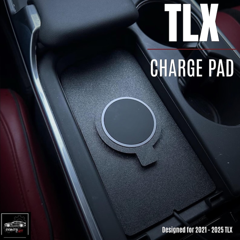 May include: Black TLX Charge Pad designed for 2021-2025 models. The pad features a circular charging area with a silver border and a textured surface. The pad is designed to fit inside a car's center console.