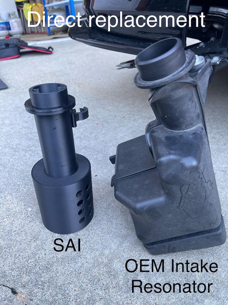 May include: Black SAI replacement part next to an OEM intake resonator. The SAI part is cylindrical with a flared top and a series of holes. The OEM part is black and irregularly shaped. Text reads "Direct replacement".