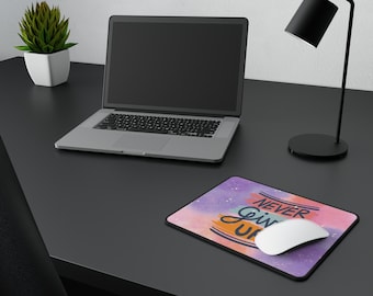 May include: A desk with a laptop, a lamp, a potted plant, and a mouse pad with the text "Never Give Up" on it. The mouse pad is a light purple color with a watercolor effect.