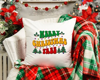May include: White throw pillow with a red, green, and yellow "Merry Christmas Tree" graphic. The pillow is on a white wicker chair with a red and green plaid throw blanket.