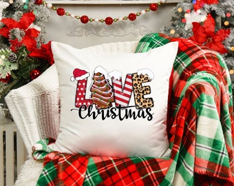 May include: White throw pillow with a festive Christmas design. The letters "LOVE" are decorated with various Christmas patterns, including a Santa hat, a gingerbread house, candy canes, and leopard print. The text "Christmas" is written below the letters.