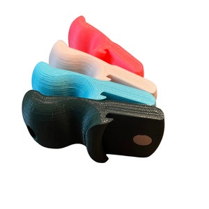 May include: Four 3D printed gun grips in different colors: black, teal, white, and pink. The grips are stacked on top of each other.
