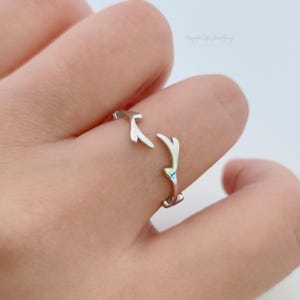 Könnte beinhalten: Ein silberner Ring mit einem zarten Hirschgeweih-Design. Der Ring ist verstellbar und kann an jedem Finger getragen werden.