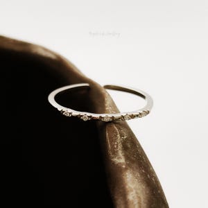 Puede incluir: Un anillo de plata con una fila de pequeñas piedras transparentes engastadas en la banda.