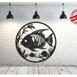 May include: Black metal wall art featuring a stylised fish with fins and a tail, surrounded by seaweed and smaller fish. The art is circular and mounted on a white brick wall.