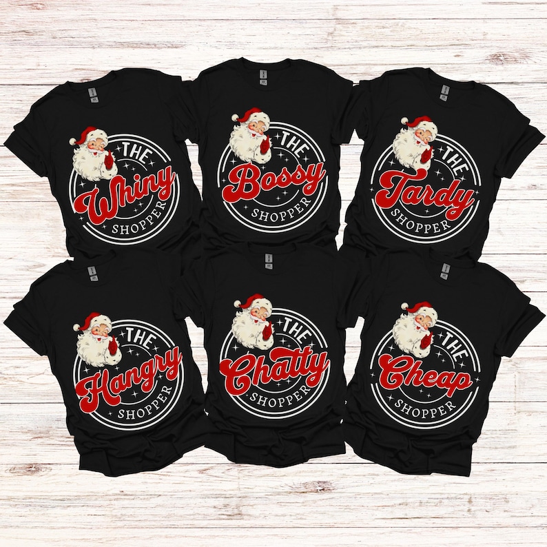 May include: Six black t-shirts with a white circle and a red Santa Claus graphic. Each shirt has a different text in the circle, including "The Whiny Shopper", "The Bossy Shopper", "The Tardy Shopper", "The Hangry Shopper", "The Chatty Shopper", and "The Cheap Shopper".