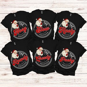 May include: Six black t-shirts with a white circle and red text that says "The [adjective] Shopper" with a cartoon Santa Claus inside the circle. The adjectives are "Nosey", "Slow", "Hasty", "Rowdy", "Greedy", and "Pushy".