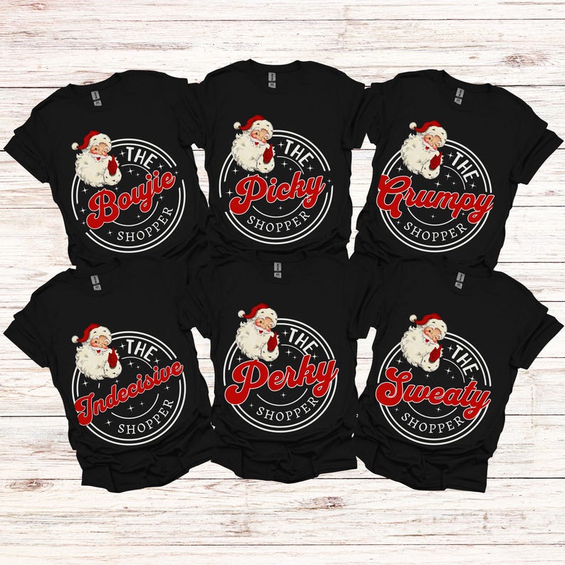 May include: Six black t-shirts with a white circle design featuring a cartoon Santa Claus and text that reads "The [adjective] Shopper". The adjectives are "Bougie", "Picky", "Grumpy", "Indecisive", "Perky", and "Sweaty".