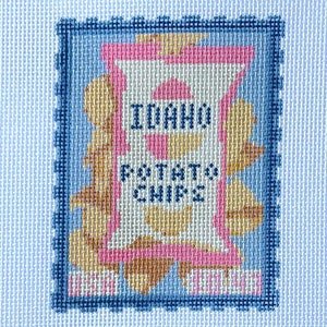 May include: A blue and white cross-stitch design of a bag of potato chips with the text "Idaho Potato Chips".