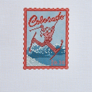 May include: Needlepoint canvas featuring a vintage-style design of a skier with the word "Colorado" in red script. The image is framed with a red border and set against a light blue background. The text "G&H" is at the bottom.