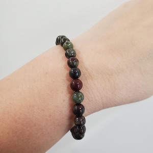 May include: A beaded bracelet with dark green, red and black beads.