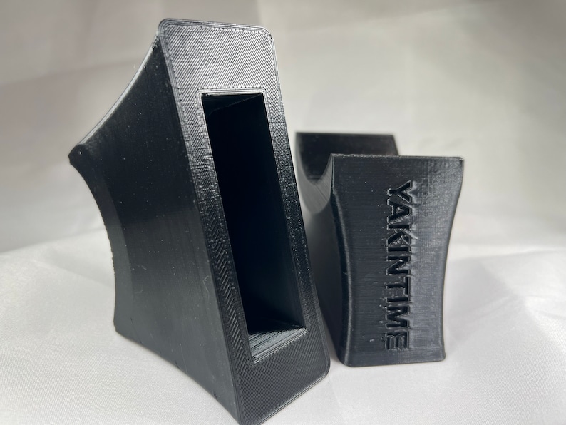 Pu&ograve; includere: Due supporti per telefono stampati in 3D di colore nero. Un supporto ha un ritaglio rettangolare e l'altro supporto ha la parola "YAKINTIME" stampata su di esso.