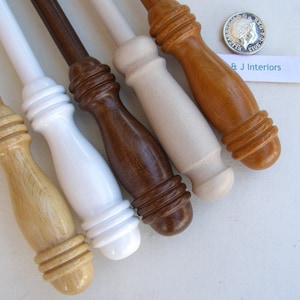 May include: Five wooden curtain rods with different finishes: natural wood, white, brown, light wood, and a reddish brown. The rods have a decorative knob at the end.