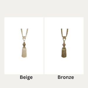 May include: Two curtain tiebacks with tassels. The tieback on the left is beige and the tieback on the right is bronze.
