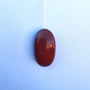 May include: A dark red oval-shaped light pull with a white cord.
