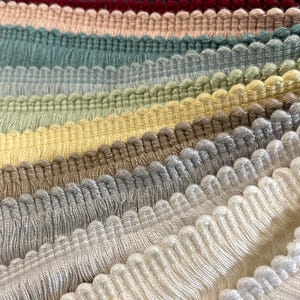May include: A selection of fringe trim in various colours, including navy, burgundy, peach, sage green, light green, yellow, beige, grey, white and ivory.